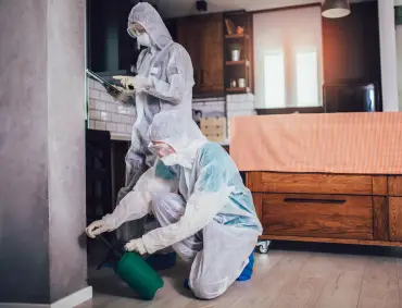 Pest control technician inspecting and applying treatment in a healthcare facility.